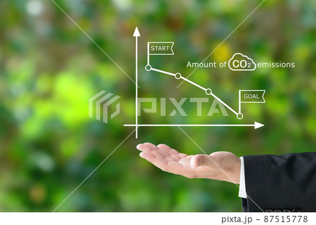 二酸化炭素排出量のグラフを掲げるビジネスマンの手元 87515778