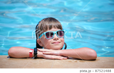 Portrait of happy child girl relaxing on swimming pool side on sunny summer day during tropical holidays Portrait of happy child girl relaxing on swimming pool side on sunny summer day during tropical holidays 87521488