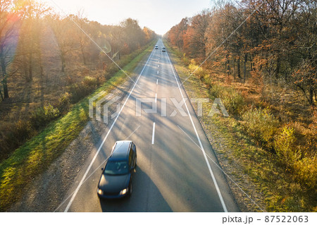 Aerial view of intercity road with blurred fast driving car at sunset. Top view from drone of highway traffic in evening Aerial view of intercity road with blurred fast driving car at sunset. Top view from drone of highway traffic in evening 87522063