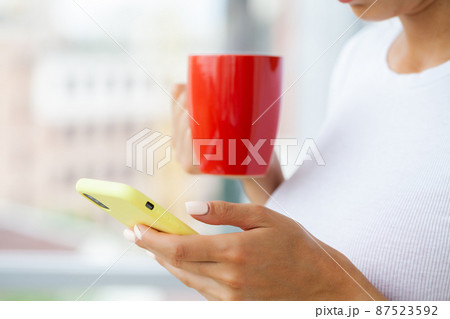 A young brunette woman looks at the mobile phone screen A young brunette woman looks at the mobile phone screen 87523592