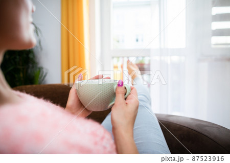 A woman's hand holds a large mug of fresh coffee. 87523916