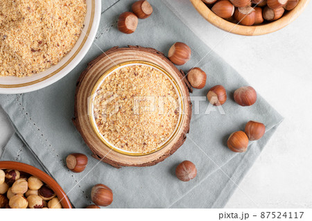 Raw Organic Ground Hazelnut Flour in a Bowl with whole nuts on grey stone background. Alternative nut flour 87524117