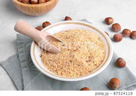 Raw Organic Ground Hazelnut Flour in a Bowl with whole nuts on grey stone background. Alternative nut flour 87524119