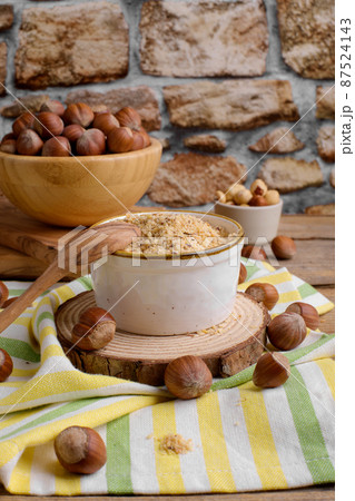 Raw Organic Ground Hazelnut Flour in a Bowl with whole nuts on rustic wooden background. Alternative nut flour 87524143