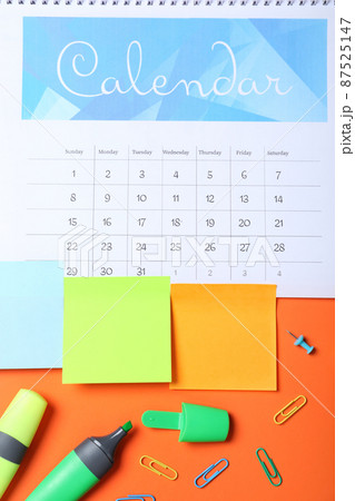 Calendar page and office stationery on orange background, flat lay 87525147