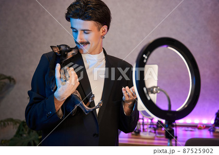 Brunette man with mustaches looking at his lovely dog and shooting together at the smartphone 87525902