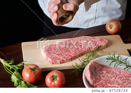 国産和牛ロースステーキ肉に胡椒をふりかける料理人 87526734