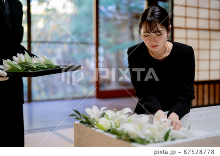 お葬式の納棺で花入れの儀をする日本人女性 87528778