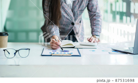 Close up a Business woman using calculator and laptop for doing math finance on a wooden desk, tax, accounting, statistics, and analytical research concept. 87531698