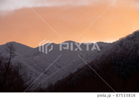 冬の夕暮れ、オレンジ色に染まった雲と冠雪の山とのコラボレーションが綺麗 87533816