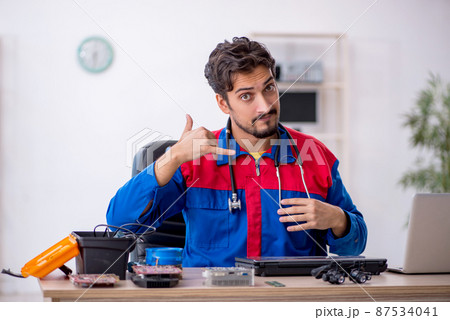 Young male repairman repairing computer Young male repairman repairing computer 87534041