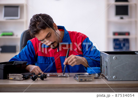 Young male repairman repairing computer Young male repairman repairing computer 87534054