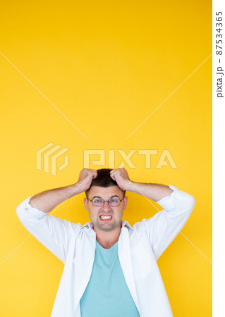 Difficult problem. Overload man. Desperate feelings. Shocked outrage guy grasping hair with hands meeting unexpected situation isolated yellow. Difficult problem. Overload man. Desperate feelings. Shocked outrage guy grasping hair with hands meeting unexpected situation isolated yellow. 87534365