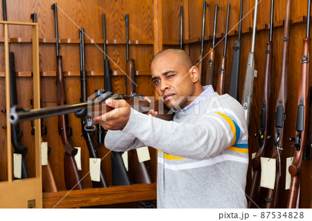 Portrait of confident man in gun shop showing rifle Portrait of confident man in gun shop showing rifle 87534828