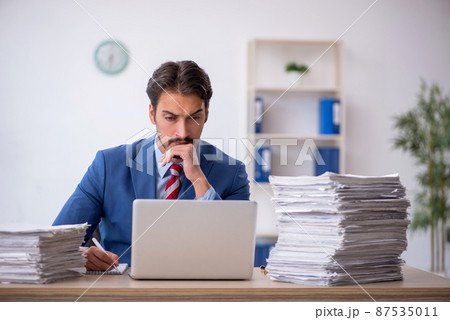 Young male employee and too much work in the office 87535011