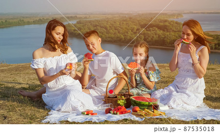 Mother and happy children have festive picnic on green hill 87535018
