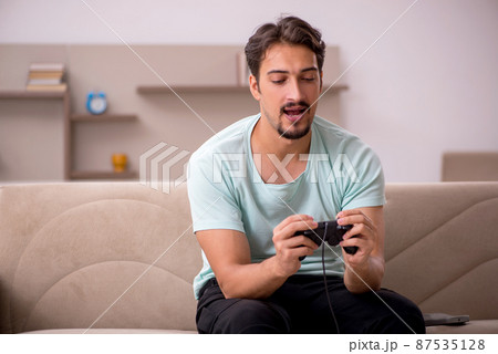 Young man playing joystick games at home 87535128