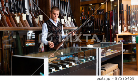 Adult owner of the gun shop demonstrates rare collectible hunting rifle Adult owner of the gun shop demonstrates rare collectible hunting rifle 87535459