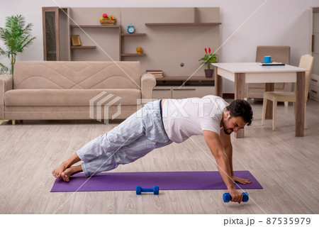 Young man doing sport exercises at home 87535979