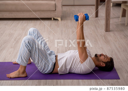 Young man doing sport exercises at home 87535980