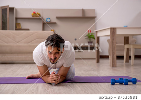 Young man doing sport exercises at home 87535981