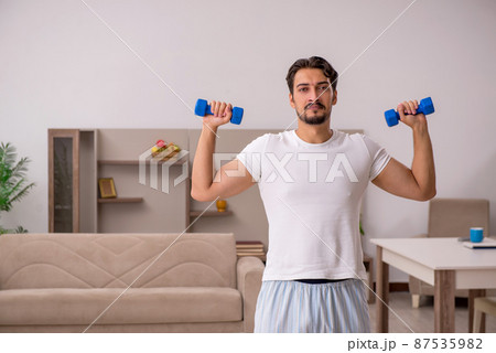 Young man doing sport exercises at home 87535982
