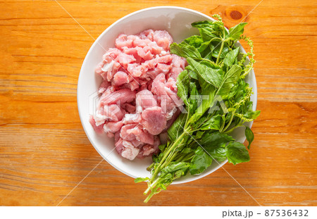 Raw pork chops on a plate with basil leaves 87536432