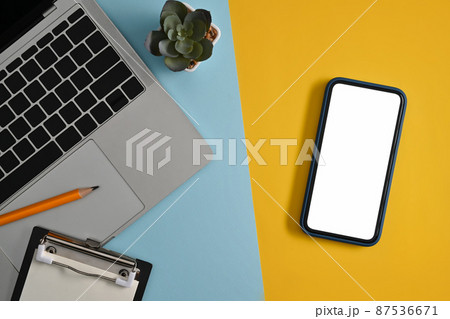 Creative workplace with smart phone, computer laptop and succulent plants on colorful background. 87536671