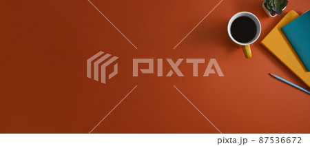 Horizontal photo of creative workplace with notebooks, coffee cup and succulent plants on orange background. Horizontal photo of creative workplace with notebooks, coffee cup and succulent plants on orange background. 87536672