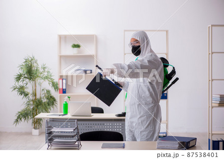Young male contractor disinfecting office during pandemic 87538401