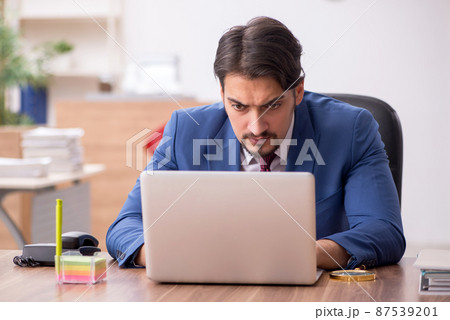 Young male employee sitting at workplace 87539201