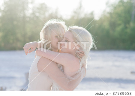 Beautiful lesbian couple walking on sand along river bank on their wedding day 87539658
