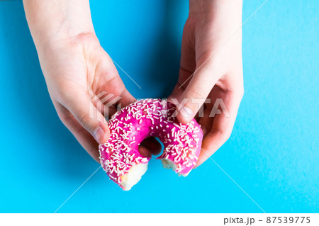 Hand holding a half eaten sweet pink donut isolated. Half eaten donut isolated. Hand holding a half eaten sweet pink donut isolated. Half eaten donut isolated. 87539775