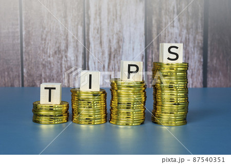 Tips text on wooden block cube on gold coins. Business concept. Tips text on wooden block cube on gold coins. Business concept. 87540351