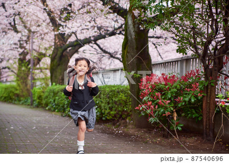 桜道を走る新一年生の女の子 87540696