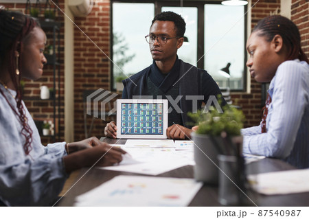 Business company marketing team leader presenting team financial data on modern tablet. 87540987