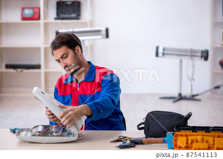 Young male repairman repairing heater Young male repairman repairing heater 87541113