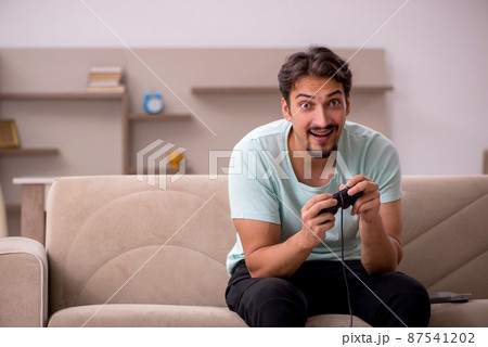Young man playing joystick games at home Young man playing joystick games at home 87541202