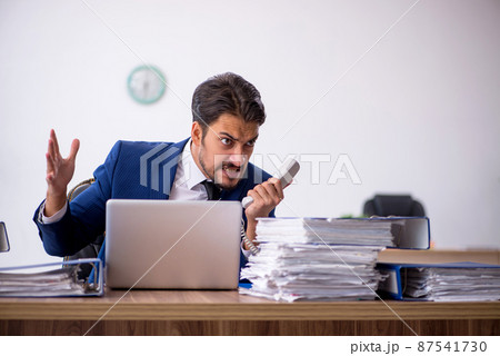 Young male employee and too much work in the office Young male employee and too much work in the office 87541730