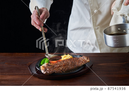 熱々のロースステーキにソースをかける料理人 87541936