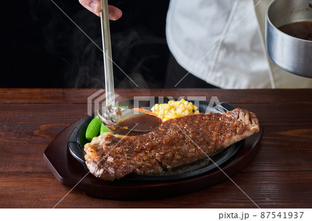 熱々のロースステーキにソースをかける料理人 熱々のロースステーキにソースをかける料理人 87541937