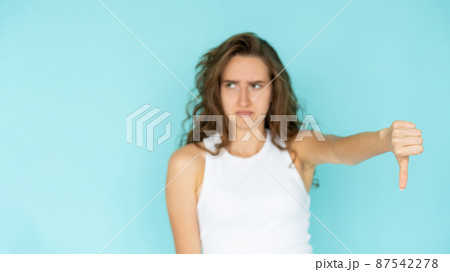 Dislike gesture. Displeased woman. Bad solution. Dissatisfied defocused pretty lady showing thumb down expressing false choice isolated blue. 87542278
