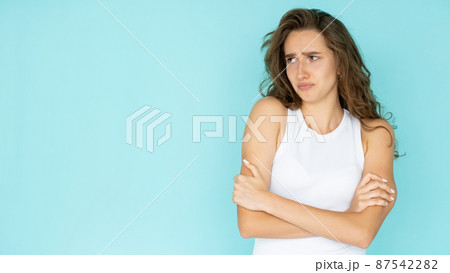 Displeased situation. Offended woman. Unhappy feelings. Upset pretty lady in white dress crossing hands on chest isolated blue looking copy space. 87542282