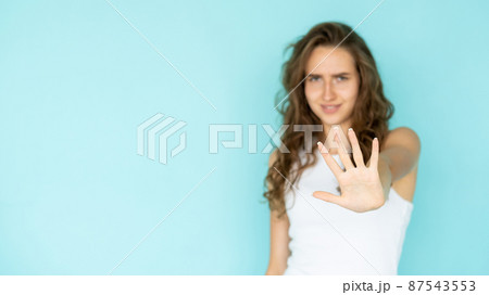 Stop gesture. Protesting woman. No way. Gloomy defocused lady in white dress holding forbidden hand up isolated blue copy space. Stop gesture. Protesting woman. No way. Gloomy defocused lady in white dress holding forbidden hand up isolated blue copy space. 87543553
