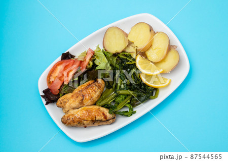 Grilled caviar cod fish with greens and fresh lemon on white small plate. 87544565