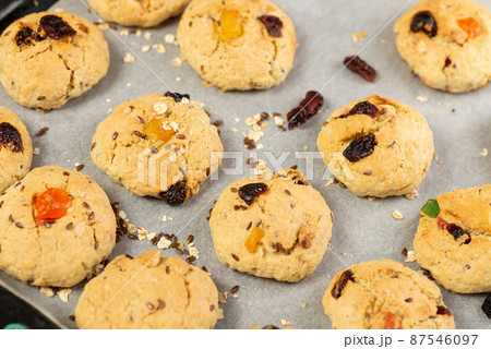 Refrigeration of freshly baked soft oatmeal cookies with raisins, candied fruits, flax and sesame seeds and walnuts on baking paper 87546097