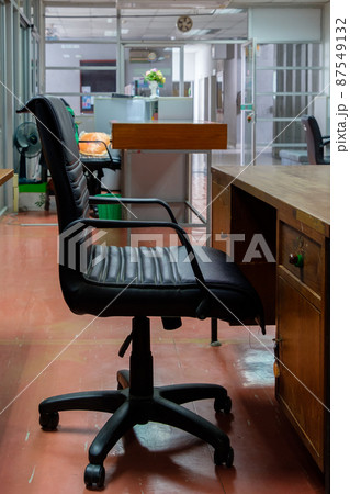 The black leather armchair near the old wooden table in the local office. The black leather armchair near the old wooden table in the local office. 87549132