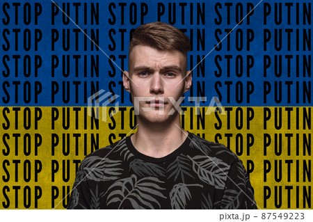 Portrait of young man asking to stop Putin isolated over blue and yellow flag background with lettering 87549223