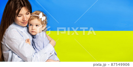 Portrait of young woman, mother with her little girl, daughter isolated over blue and yellow Ukrainian flag background. Flyer Portrait of young woman, mother with her little girl, daughter isolated over blue and yellow Ukrainian flag background. Flyer 87549906