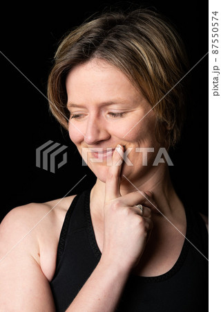 Low key studio portrait of a 35 year old white woman, playful thinking look 87550574